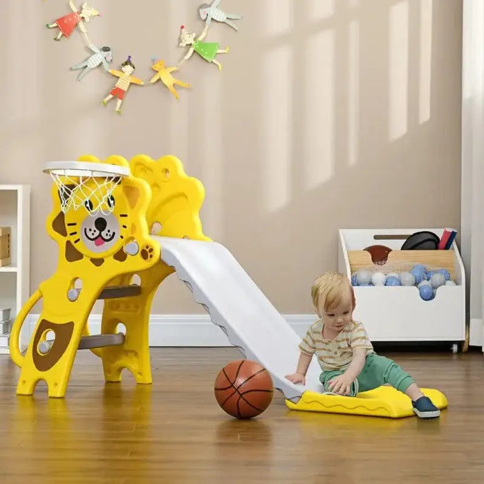 Toddler on yellow lion-themed indoor slide with basketball hoop and ball on wooden floor