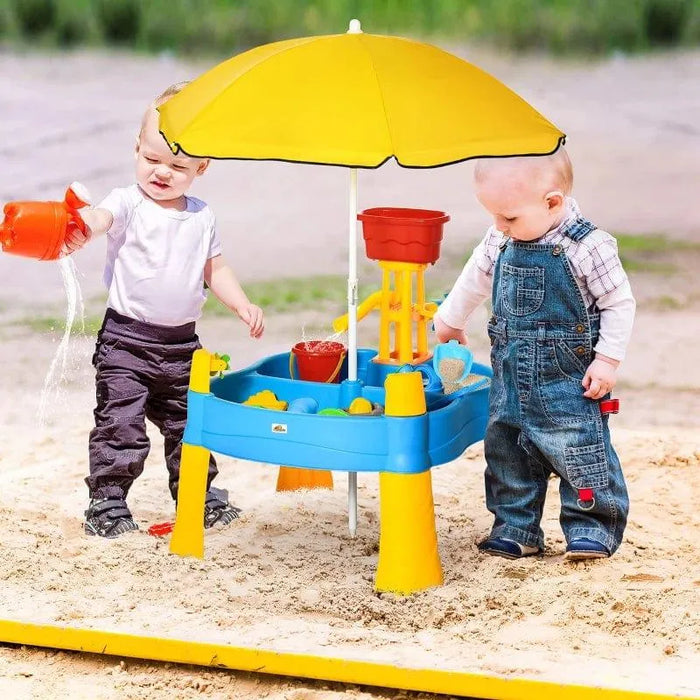 Toddlers playing at a 2-in-1 sand and water activity table with a yellow umbrella outdoors