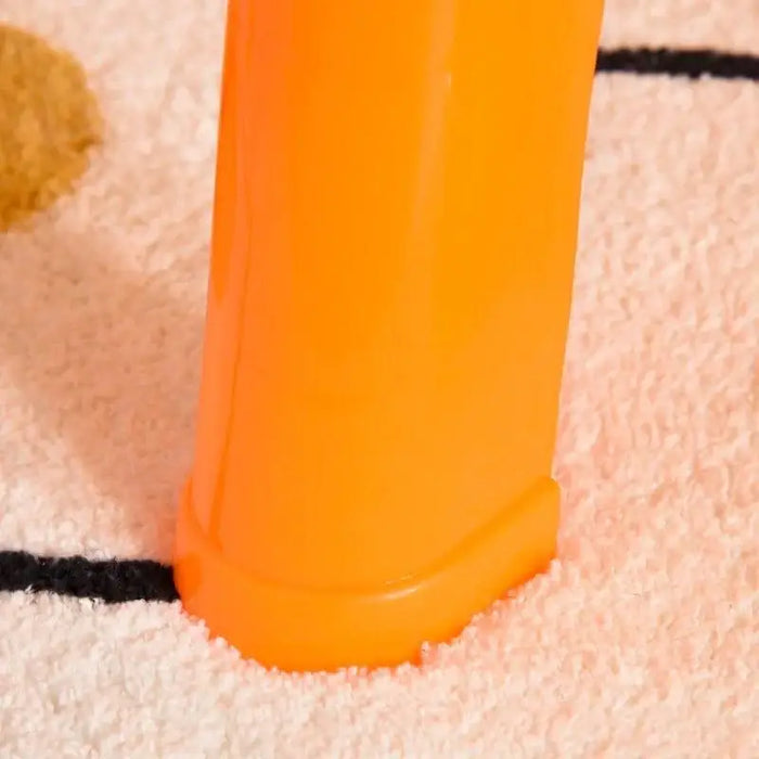 Close-up of orange plastic leg of sand and water table on light textured rug