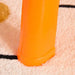Close-up of orange plastic leg of sand and water table on light textured rug