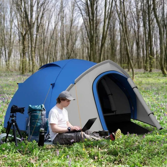 Blue and grey 2-person dome tent with front vestibule set up in a forest clearing
