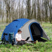 Blue and grey 2-person dome tent with front vestibule set up in a forest clearing