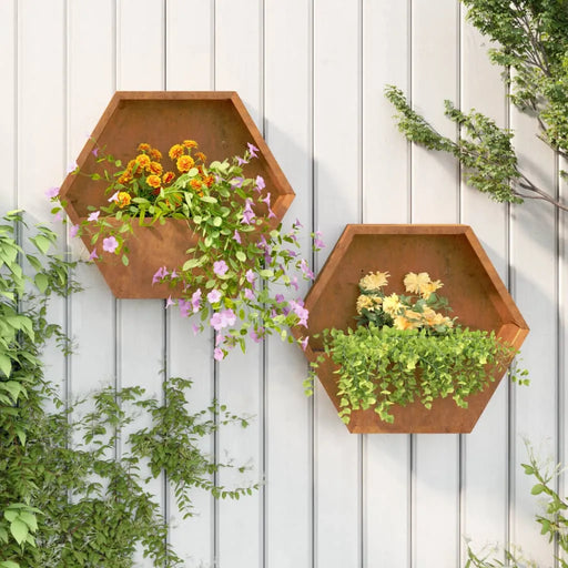 Hexagonal corten steel wall planters with vibrant orange and yellow flowers on white outdoor panel wall