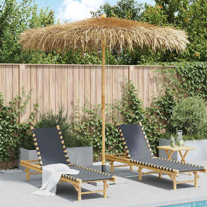 Tropical banana leaf garden parasol with bamboo pole over two lounge chairs by a pool