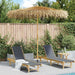 Tropical banana leaf garden parasol with bamboo pole over two lounge chairs by a pool