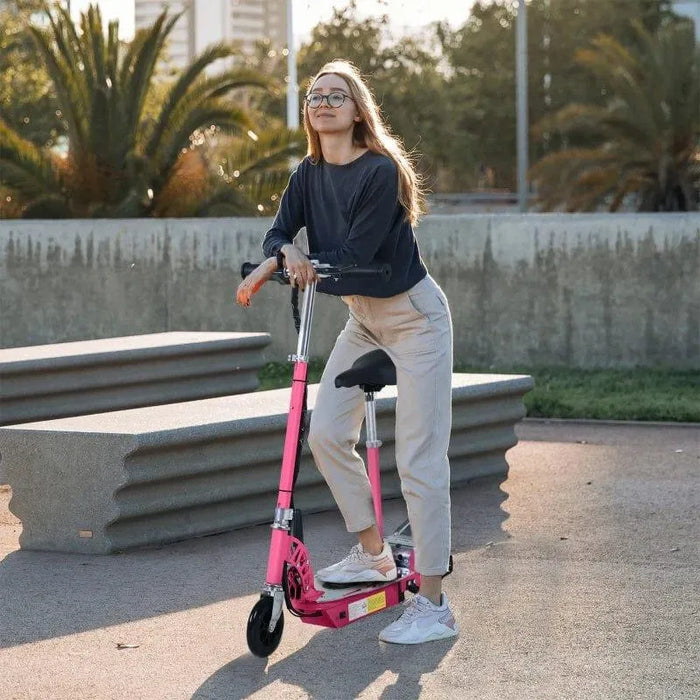 Woman with glasses on a pink electric scooter with seat outdoors near concrete benches