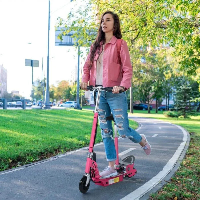 Woman riding pink 24V electric scooter with adjustable seat on park path, foldable design