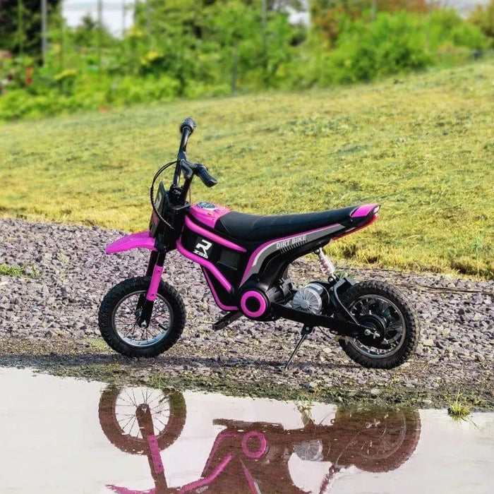 Pink 24V kids electric dirt bike with black details on gravel next to grass and puddle