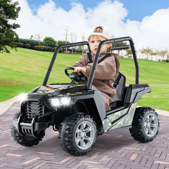 Toddler boy driving camouflage electric ride-on car with headlights on on paved path