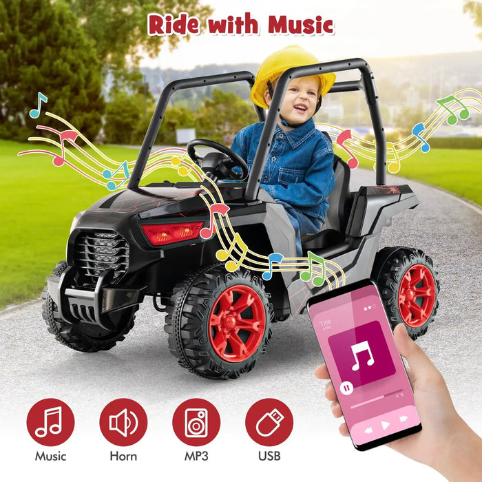 Child wearing yellow helmet riding black and gray electric toy car with red wheels outdoors, music streaming from smartphone