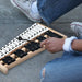 Person playing wooden glockenspiel xylophone with black and white keys while sitting on concrete floor