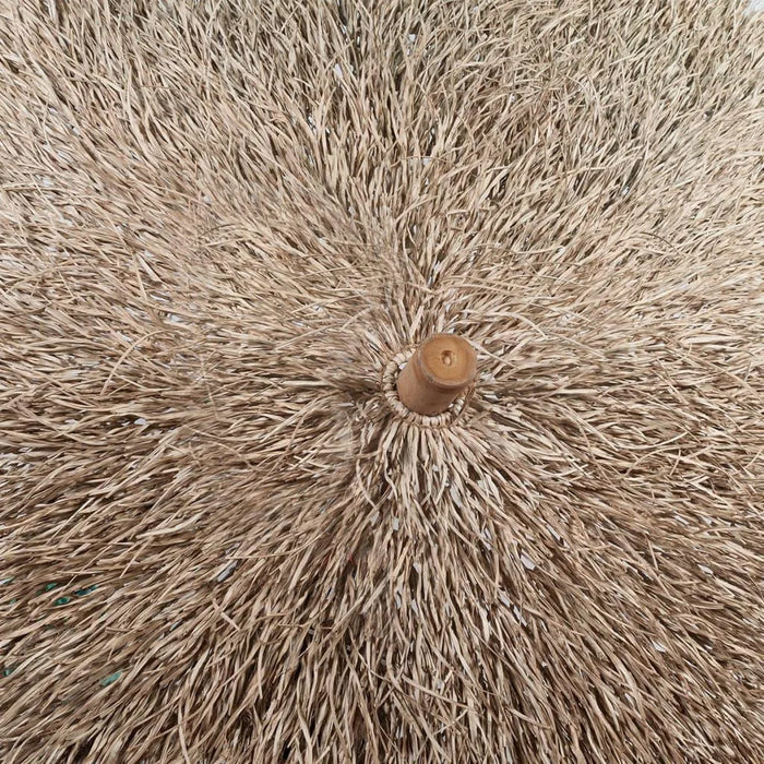 Close-up of a hand-woven straw garden parasol with bamboo pole, tropical design
