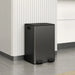 Black trash bin against a white wall with horizontal lines