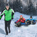 Man in green jacket pulling two kids on a blue inflatable snow tube in snowy forest