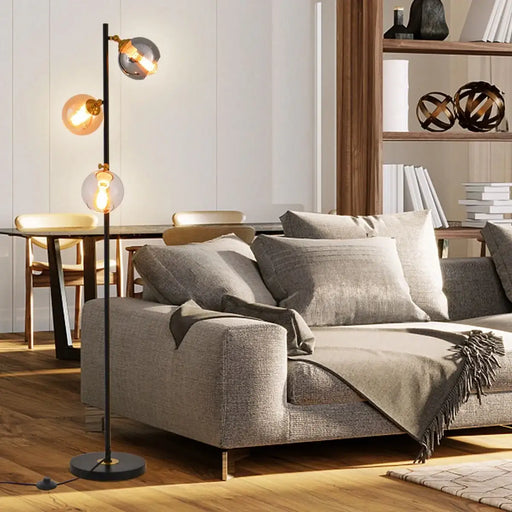 Modern living room with a gray sofa, floor lamp, and bookshelf.