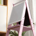Pink wooden kids easel with whiteboard in modern room with plants and sunlight