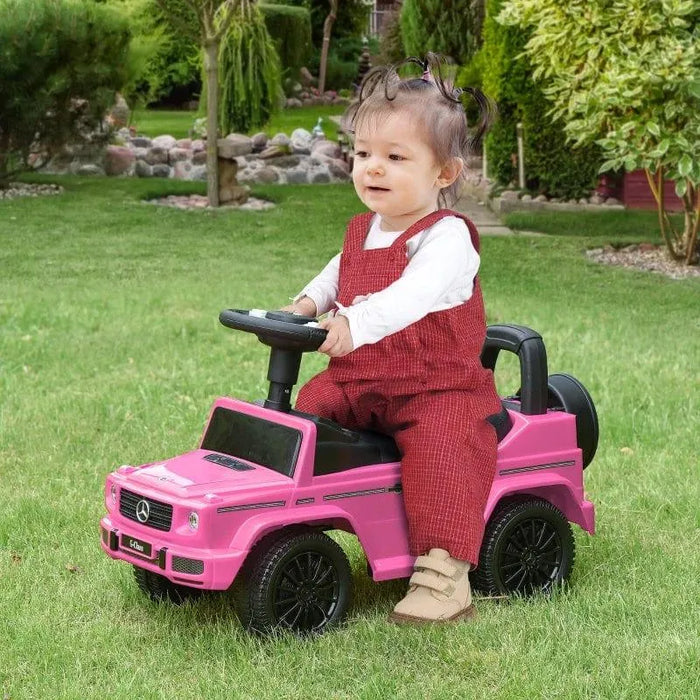 Toddler riding pink Mercedes Benz G350 kids sliding car toy on grass in garden