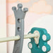 Close-up of toddler swing and slide set with crown-shaped gray support and teal connector