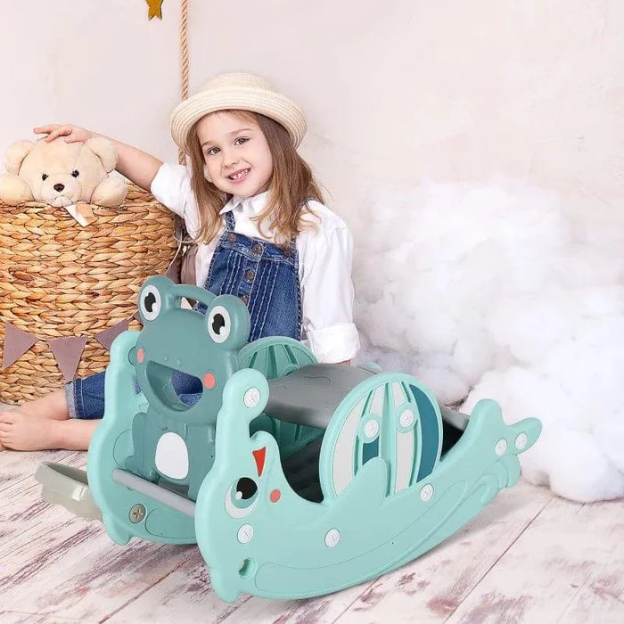 Smiling girl with a straw hat plays on green 3-in-1 frog and dolphin rocking horse toy indoors