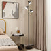 Modern floor lamp in a bedroom setting with a bed, nightstand, and abstract art on the wall.