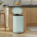 Modern kitchen with a light blue trash can on a wooden floor.