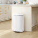 White trash bin in a kitchen setting with light wood flooring and neutral color palette.
