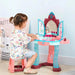 Child playing at colorful kids dressing table with stool, toy mirror and pretend cosmetics