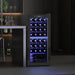 Wine cooler with illuminated interior displaying bottles in a dark room setting.