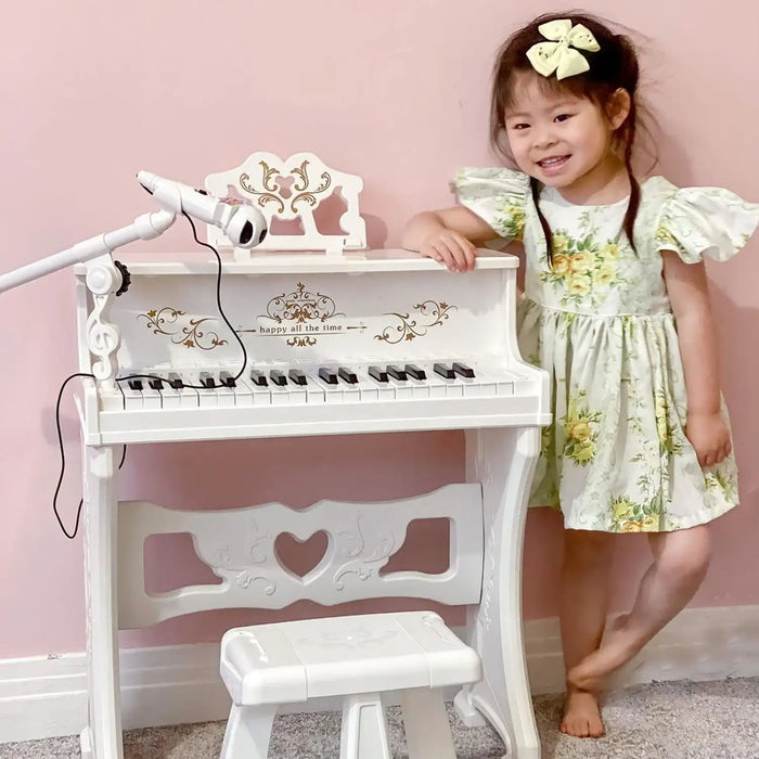 Smiling girl in floral dress with 37-key white kids piano, mic, and stool in pink room