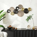 Decorative wall art with circular patterns on a white wall above a black console table.