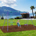 Child on purple and blue garden swing set with lake and mountains in the background