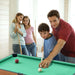 Family playing pool together in a room with light-colored walls.