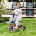 Child riding navy 4-in-1 balance trike with orange wheels in backyard, ASTM and CPSIA certified