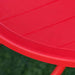 Close-up of red round kids' table on green grass, part of outdoor dining set