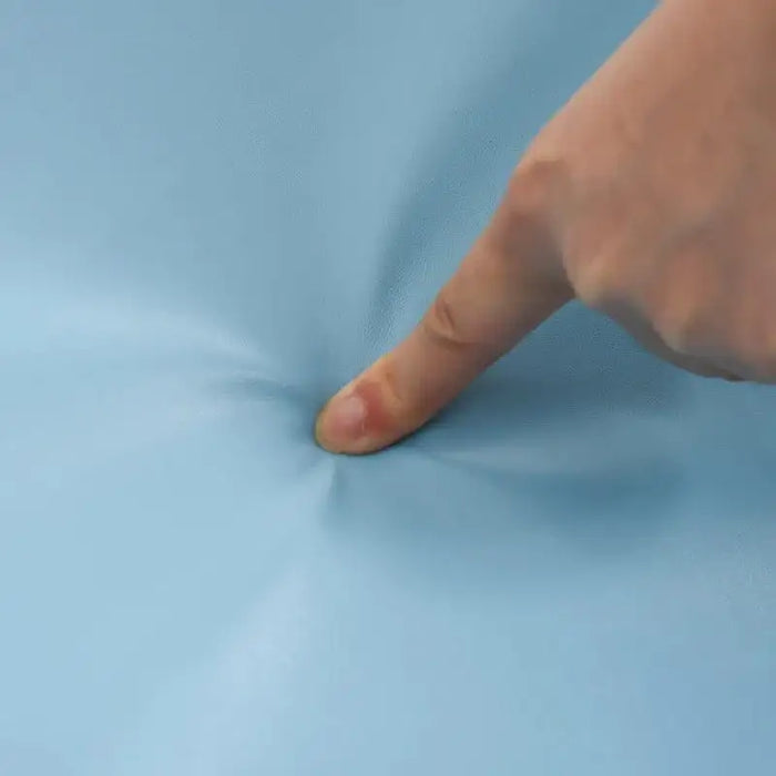 Finger pressing into soft blue foam play mat close-up