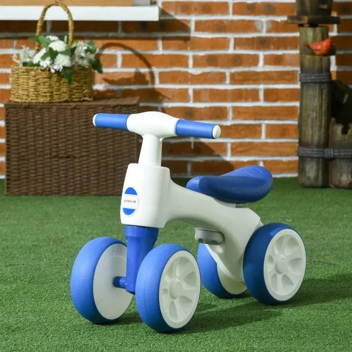 White and blue 4-wheel kids balance bike on artificial grass with brick wall background