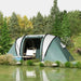 Dark green tunnel tent with chair and cooler by a pond in a forest campsite setting