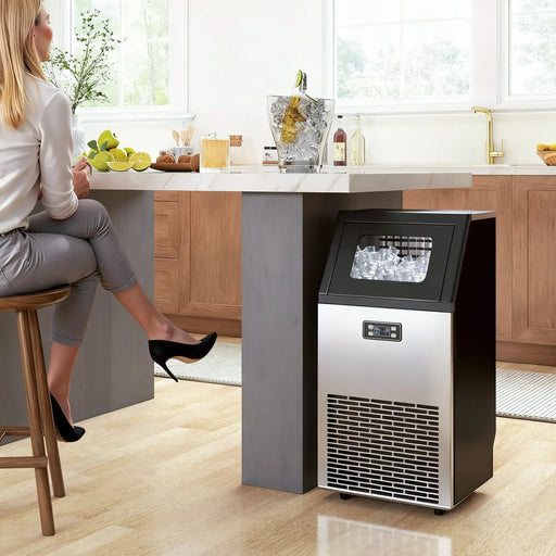 Woman sitting at a kitchen counter with an ice maker in the foreground