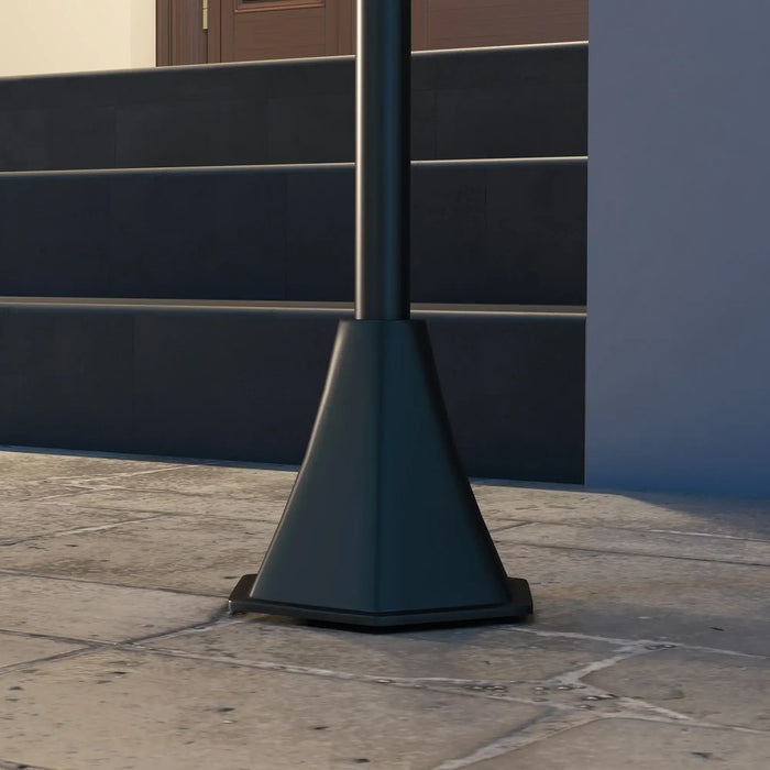 Black metal street lamp base on stone tile pavement near dark stairway with handrail