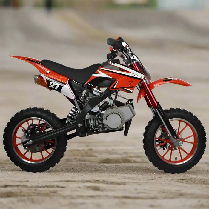 Red mini dirt bike for kids, off-road motorcycle on sandy surface, side view