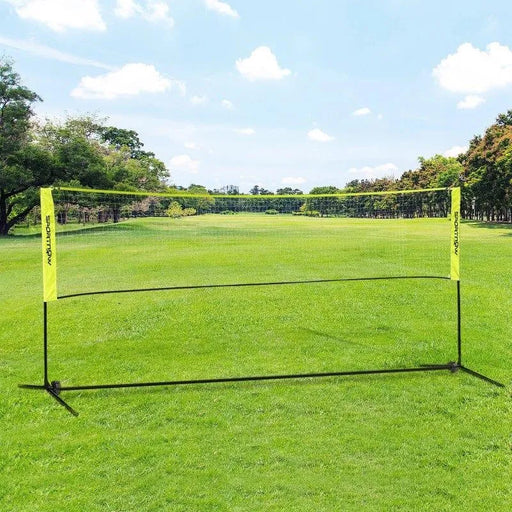 Portable badminton net with adjustable height set up on green grass field outdoors