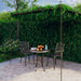 Wrought iron lean-to garden pergola with climbing plants over outdoor table and chairs