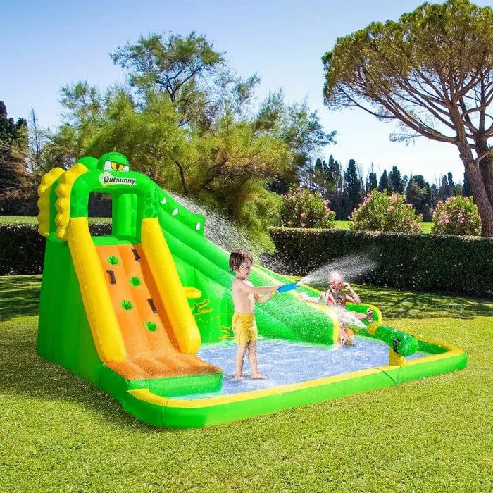 Kids playing on inflatable bounce house water slide with climbing wall and pool in garden