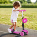 Child riding pink 5-in-1 kids kick scooter with cartoon front, outdoors on track
