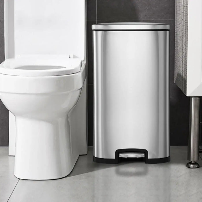 Silver trash can next to a white toilet in a bathroom setting