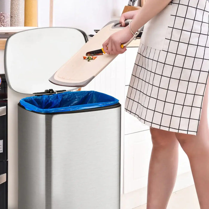 Person disposing of food waste into a trash can with a blue liner.