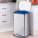 Silver trash bin with blue liner in a kitchen setting
