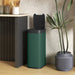 Green touchless sensor trash bin with open black lid beside kitchen counter and potted plant