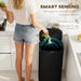 Person disposing of vegetables into a smart sensing trash can in a kitchen.