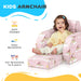 Toddler sitting on pink unicorn-themed kids armchair with soft padded cushion and footrest